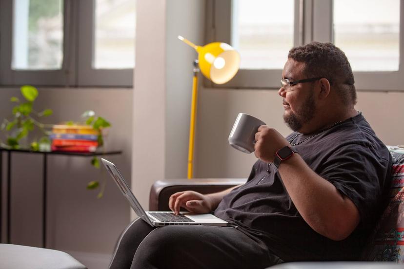gabriel_silva (1) Um homem sentado olhando para o notebook segurando uma caneca