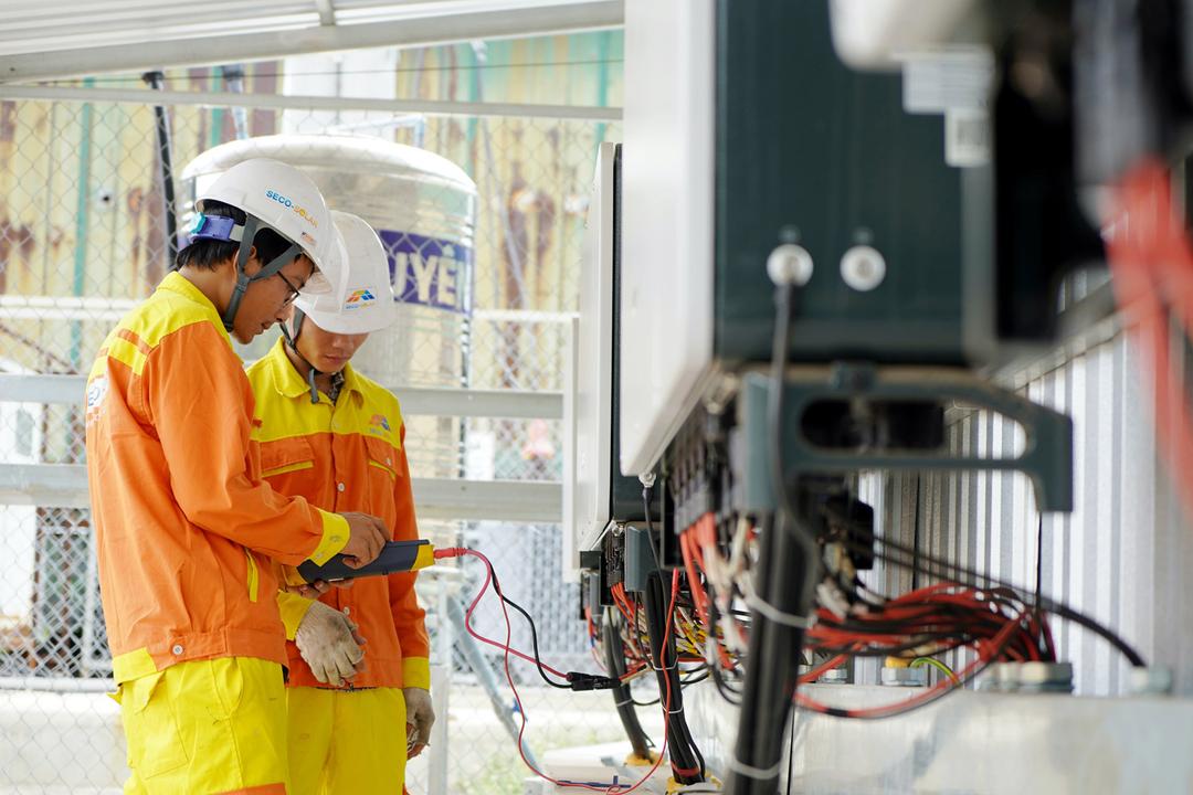 Trabalhadores com EPI usando equipamentos eletrônicos