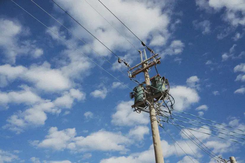 Smart energy system predicting power grid failures Utility pole with transformer and electrical cables under a blue sky with clouds, representing a smart energy system in the power grid