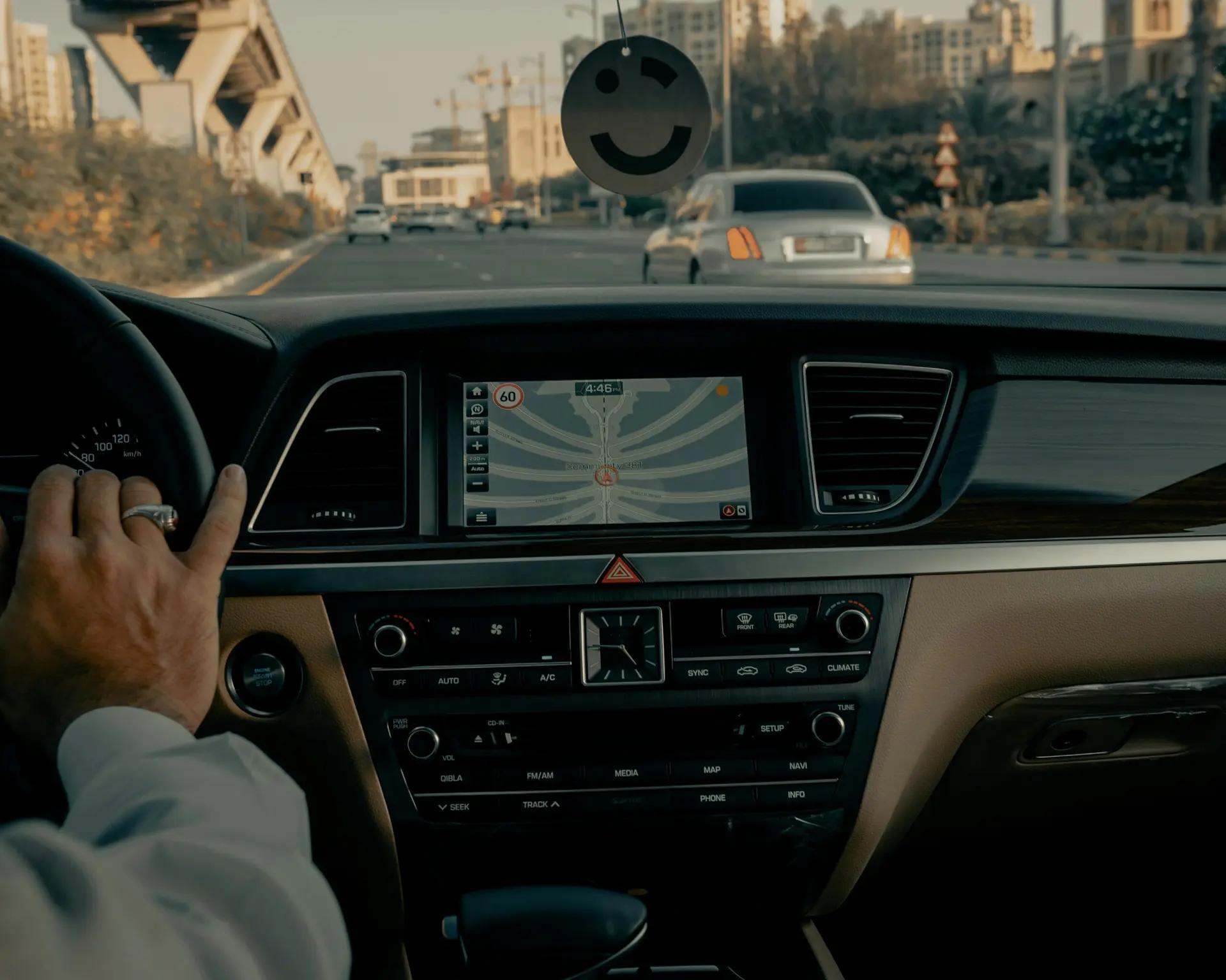 Segurança veicular e inovações tecnológicas no painel de carros modernos Interior de carro em movimento com foco no painel digital exibindo mapa GPS e mãos do motorista ao volante na estrada.