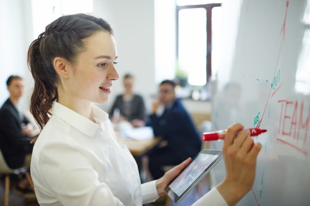 Mulher branca dando aula para outros colaboradores na empresa